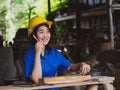 Woman working in mechanic uniform using measuring tools to cut wood sheets in factory