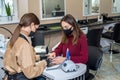 woman working in a nail salon offers a color of nail polish to one of her clients and smiles. Royalty Free Stock Photo