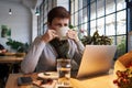 Woman working on a notebook and drinking coffee at a table in a cafe