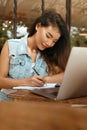 Woman. Working Online At Cafe. Asian Girl In Casual Clothes Using Laptop And Writing Something In Planner Book. Royalty Free Stock Photo