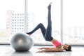 Woman working out with exercise ball in gym. Pilates woman doing exercises in the gym workout room with fitness ball. Fitness woma