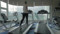 Woman working out on running machine and looking at city