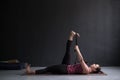 Woman working out using yogic belt, lying in yoga Supta Padangushthasana