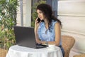 Woman working remotely with laptop and phone in cafe. Beautiful brunette using notebook in cafe. Happy businesswoman call Royalty Free Stock Photo