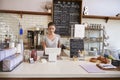 Woman working on the till at the counter of a coffee shop