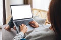 A woman working and typing on laptop computer with blank screen while lying on a sofa at home Royalty Free Stock Photo