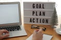 Woman working at wooden table, closeup. Light box with words Goal Plan Action on workplace