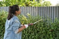 Woman working on the yard cutting bush with hedge shear at home