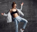 Woman workout exercise stand in silver down puffer jacket blue jeans sunglasses on loft wall with dust snow splashes Royalty Free Stock Photo