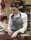Young woman works in a bag making studio, cuts out details Royalty Free Stock Photo