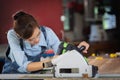 Woman works in a carpentry shop. Attractive female carpenter using some power tools for her work in a woodshop Royalty Free Stock Photo