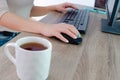 A woman works on a computer from home. Cropped image of businesswoman using computer while having tea at desk Remote work.. Royalty Free Stock Photo