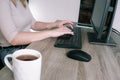 A woman works on a computer from home. Cropped image of businesswoman using computer while having tea at desk Remote work.. Royalty Free Stock Photo