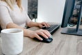 A woman works on a computer from home. Cropped image of businesswoman using computer while having tea at desk Remote work.. Royalty Free Stock Photo