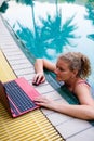 A woman works on the computer in the pool.