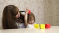 Woman works at home with a child. quarantine coronavirus. mother plays with her child in multi-colored cubes at work in