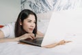 Woman works with laptop on the bed in concept of workation. Royalty Free Stock Photo