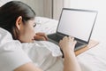 Woman works with laptop on the bed in concept of workation. Royalty Free Stock Photo