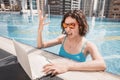 Woman works at laptop and gestures intensely during a mistake or conflict with a client with bright funny emotions in a swimming