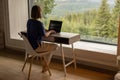 Woman works on laptop remotely in house on nature Royalty Free Stock Photo