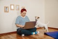 Woman works online using laptop computer, dog interferes. Quarantine coronavirus