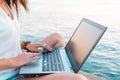 A woman works remotely on a laptop. Hands close-up. Sea in the background. The concept of freelancing Royalty Free Stock Photo