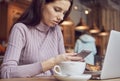 Woman works remotely online from cafe while quarantine coronavirus is in effect. Concept of checking mail, blogger, freelancer