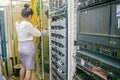 A woman works in a server room. The girl switches the wires in the routers of the Internet provider. The specialist works in the