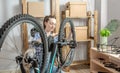 Woman in the workshop is disassembling his bike and repairing it. Concept of maintenance, preparation for the new season