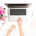 Woman workspace with female hands, laptop, pink roses bouquet, coffee mug, diary. Top view. Flat lay home office desk. Girl workin
