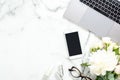 Woman workspace with laptop computer, peony flowers bouquet, smartphone, accessories, glasses on white marble background. Flat lay
