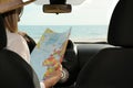 Woman with world map in car, back view. Road trip Royalty Free Stock Photo