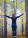 Woman worshiping with open arms in the forest in autumn