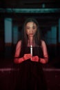 a woman worshiping satan holding a candle in her hand when a ritual is going to be held at a cemetery