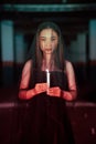 a woman worshiping satan holding a candle in her hand when a ritual is going to be held at a cemetery