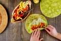 Woman wraping fried chicken with vegetable in pita bread