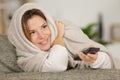 woman wrapped in blanket using remote control Royalty Free Stock Photo