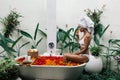 Woman relaxing in outdoor bath with flowers in Bali spa hotel Royalty Free Stock Photo
