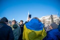 A woman wrapped in a Ukranian flag holds her phone up at an anti war protest in London