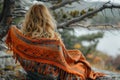 Woman wrapped in a warm orange blanket in nature