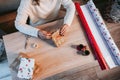 A woman wrapping a Christmas gift at home. She is sitting on the ground and she is working on a small table. There are some