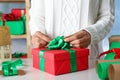 Woman wrapping Christmas gift at white wooden table, closeup Royalty Free Stock Photo