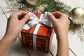 Woman wrapping Christmas gift at white wooden table, closeup Royalty Free Stock Photo