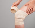 Woman wrapping elastic bandage around painful knee to relieve pain or prevent injury. Sprained ligaments, meniscus tear Royalty Free Stock Photo