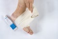 Woman is wrapping her leg with sprained ankle with elastic bandage  on white background. Twisted bandaged ankle and gel on Royalty Free Stock Photo