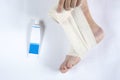 Woman is wrapping her leg with sprained ankle with elastic bandage  on white background. Twisted bandaged ankle and gel on Royalty Free Stock Photo