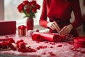 Woman wrapping valentines day gifts in festive wrapping paper with copy space for text