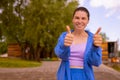 woman in wrinkle-free daily suit looking and show thumb up gesture on camera on green park background Royalty Free Stock Photo