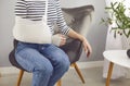 Woman with a wrist injury wearing an arm sling and a bandage sitting on an armchair at home Royalty Free Stock Photo