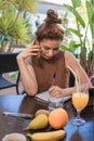 View of a woman writer and talking on her cell phone on the terrace - Tablet, fruit and orange juice on the table Royalty Free Stock Photo